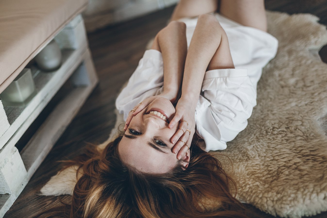 Mulher sorrindo deitada no chão com as mãos na bochecha