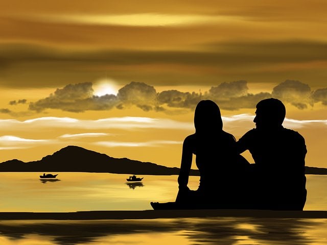 Casal sentado em frente ao mar