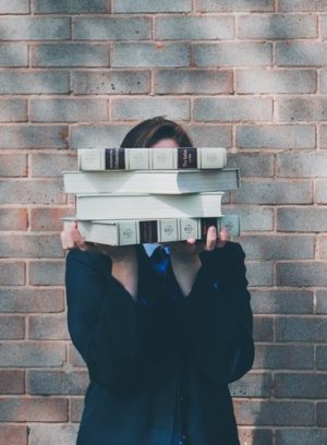 Unsplash/Siora Photography Mulher segurando livros em frente ao rosto