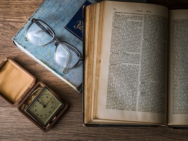 Livro com óculos e relógio ao lado