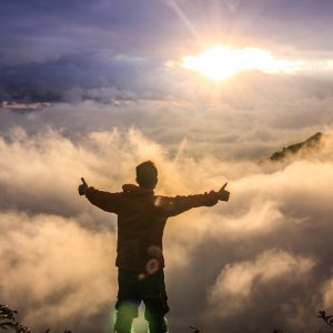 Nghia Le Unsplash Homem no topo da montanha com os braços abertos para o sol