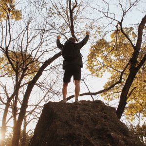Izabelle Acheson Unsplash Homem com os braços para o alto entre as árvores