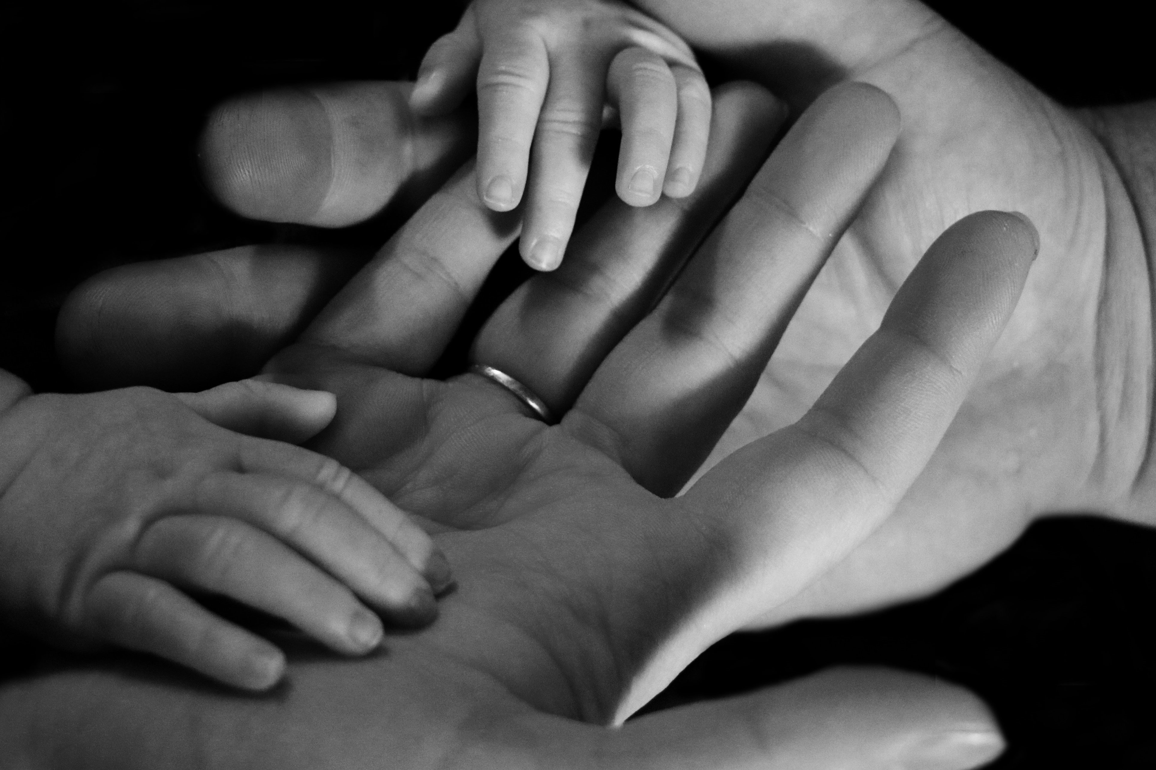Mãos de bebê entre as mãos de adultos