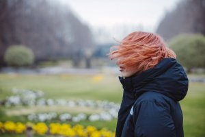Unsplash Garota parada com seus cabelos voando com o vento.