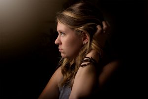 Callie Morgan/Unsplash Mulher olhando para um ponto de luz pensativa.