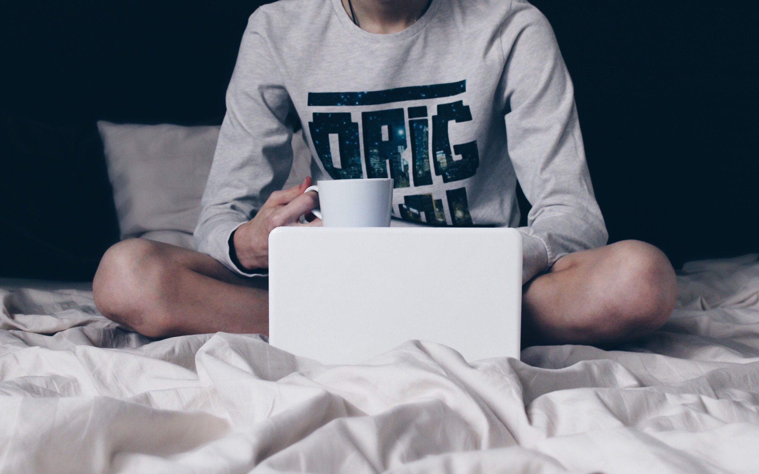 Pessoa segurando uma xícara de café na cama