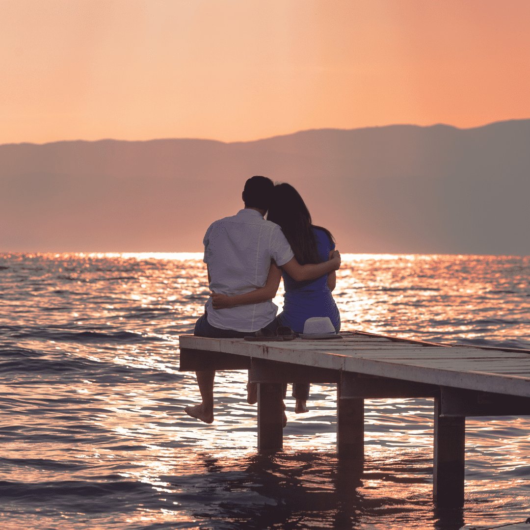 Casal sentado no deck observando o mar