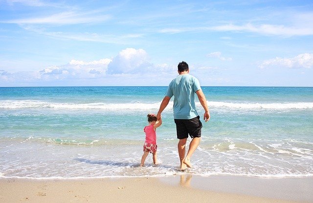 Pai e filha andando na beira do mar