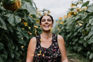 Priscilla Du Preez/Unsplash Mulher sorrindo enquanto alguma pétalas amarelas cai sobre ela.