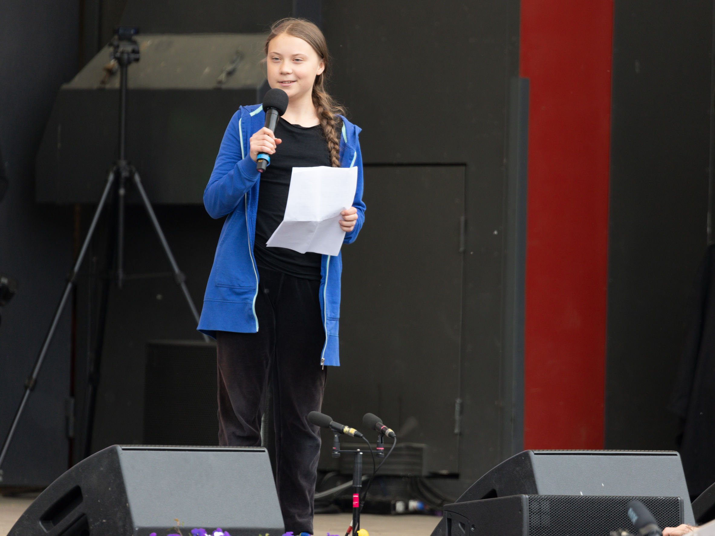 Greta Thunberg discursando em cima de palco, com microfone.