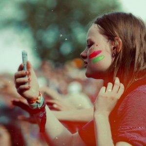 Camille G Unsplash Menina com o celular na mão em meio a várias pessoas