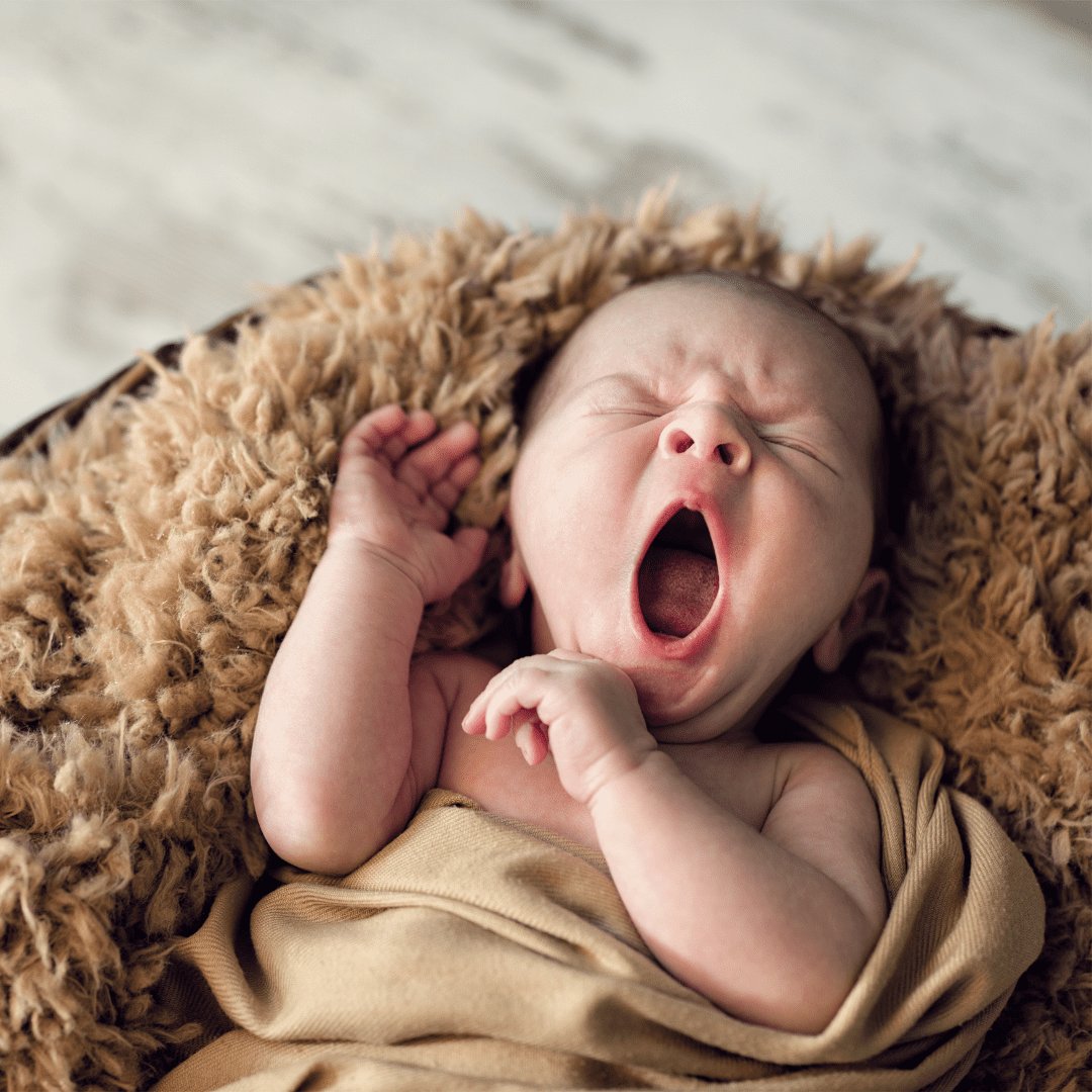 Criança deitado em um lençol bocejando