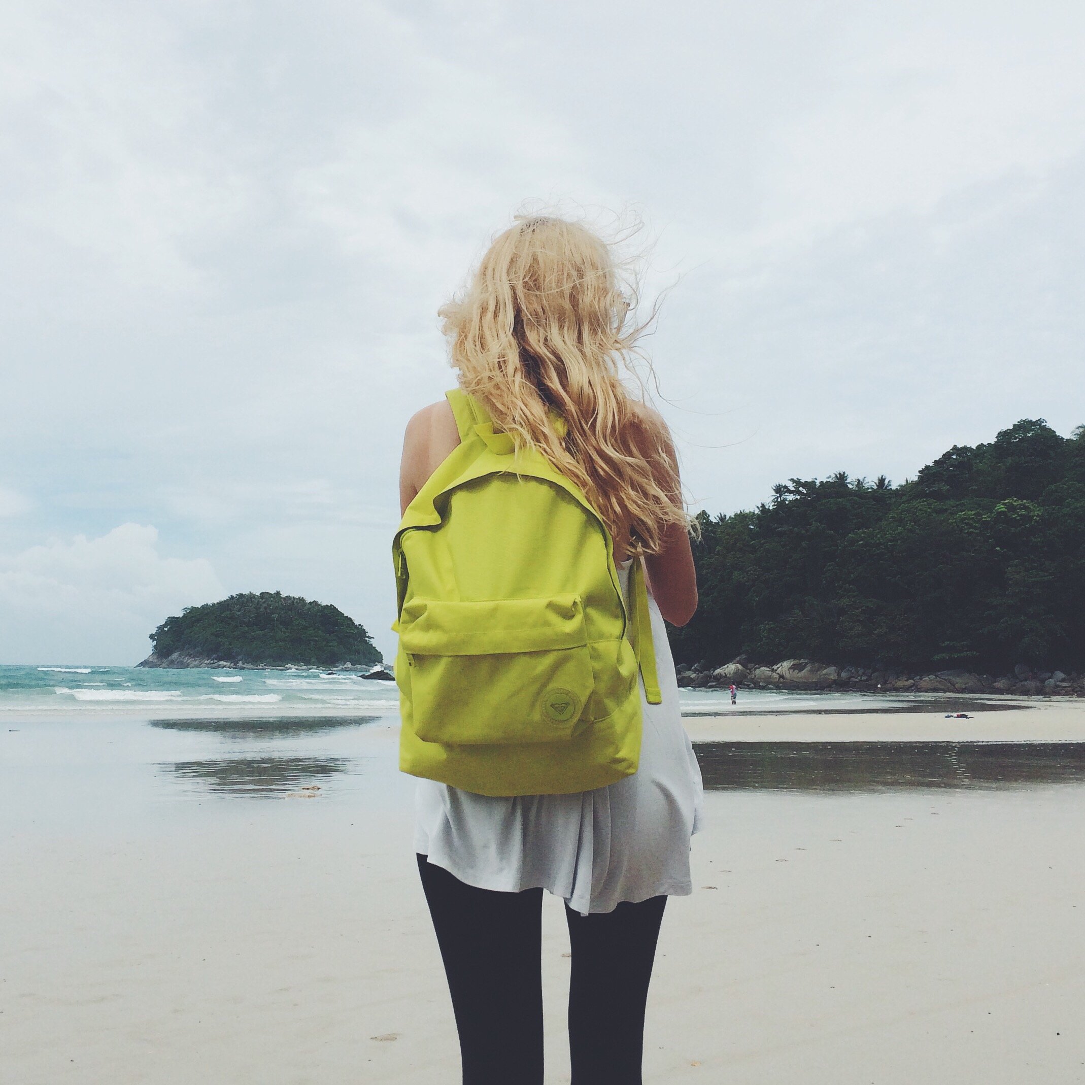 Mulher na praia com mochila nas costas