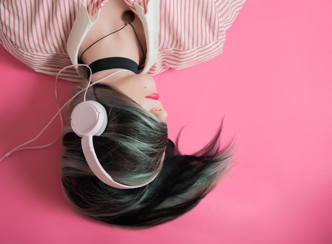 Menina com fone de ouvido em fundo rosa