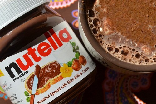 Pote de Nutella ao lado de caneca de chocolate quente