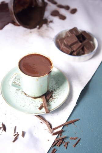 Chocolate quente em xícara e chocolates ao lado