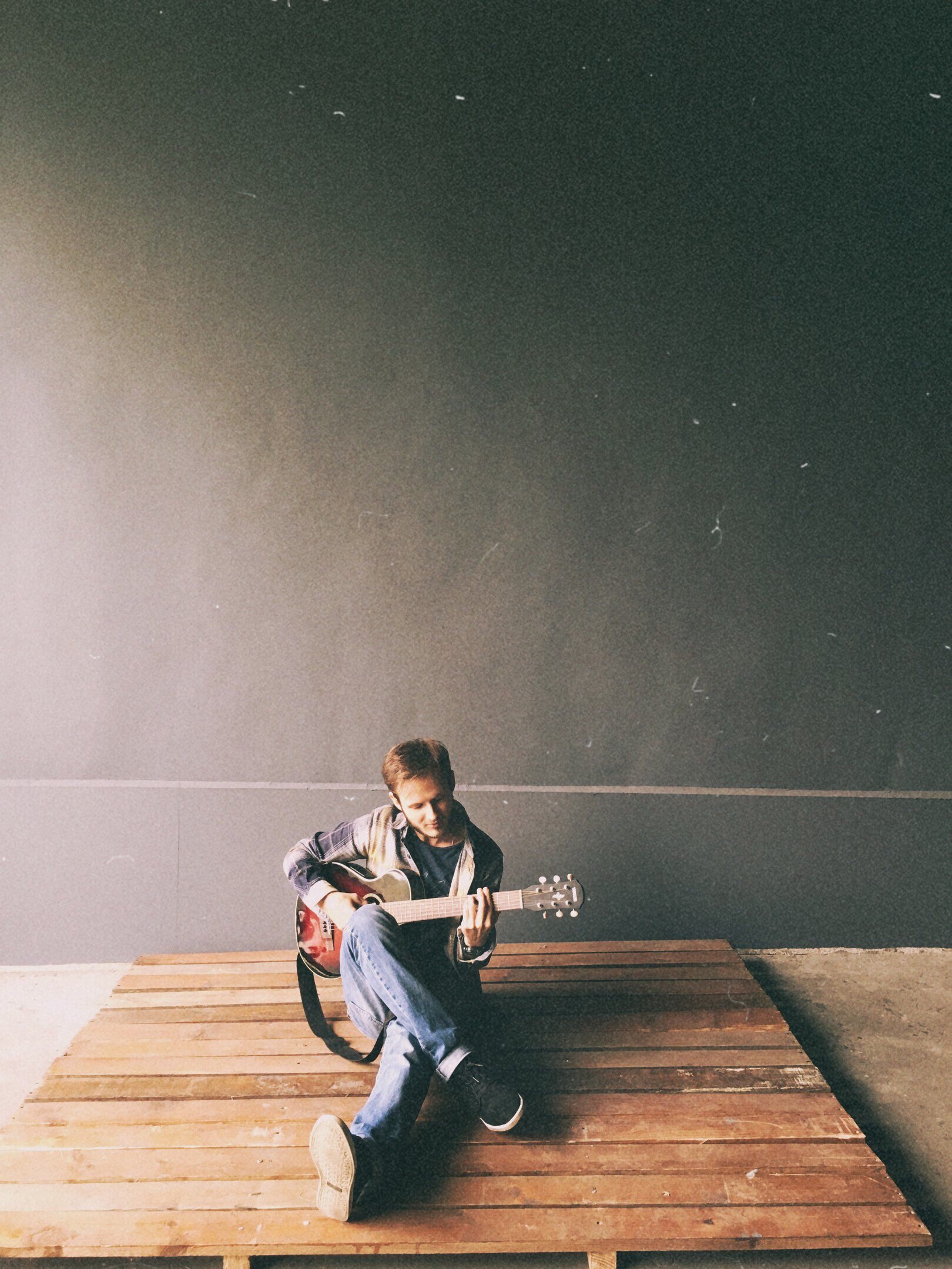 Homem sentado no chão tocando violão