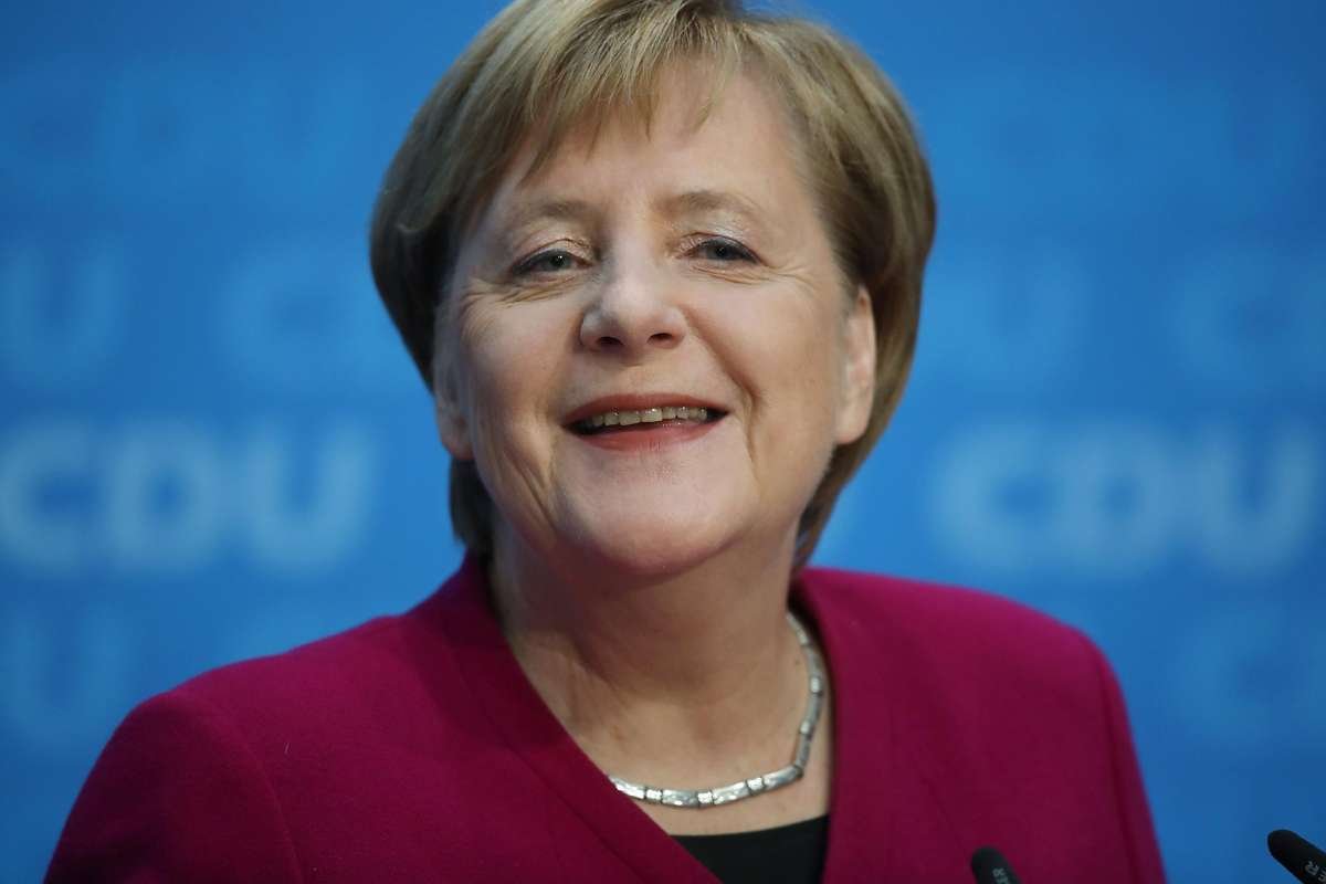 Angela Merkel sorrindo com microfone a sua frente
