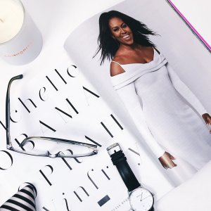 Jealous Weekrnd Unsplash Mesa com a revista com a Michelle Obama e alguns acessórios como relógio e óculos