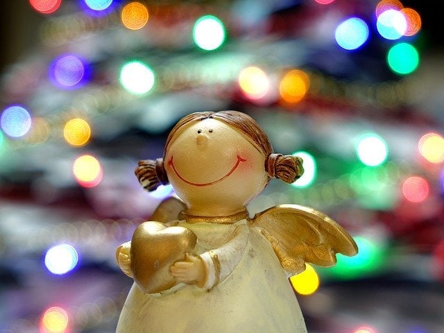 Estátua de anjo com luzes de Natal ao fundo