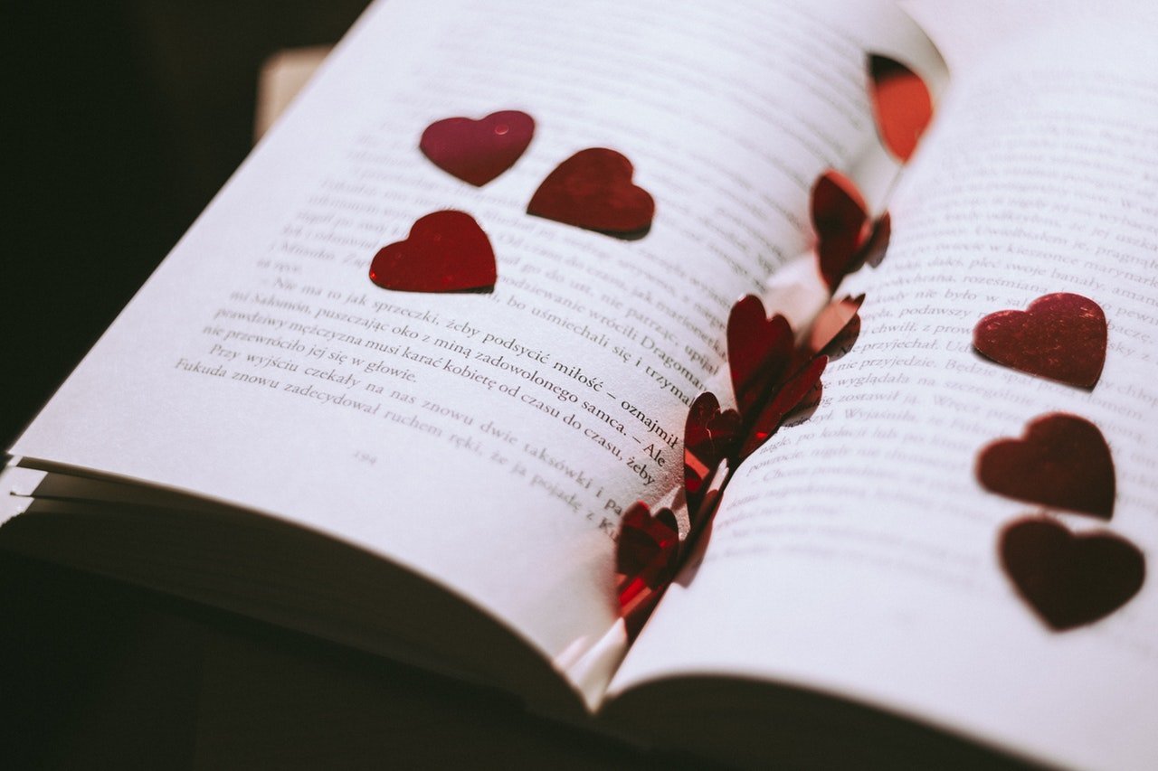 Livro aberto com corações vermelhos em cima.