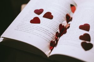 Foto de freestocks.org no Pexels Livro aberto com corações vermelhos em cima.