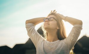 Foto de Radu Florin no Pexels Mulher sorrindo com as mãos atrás da cabeça.