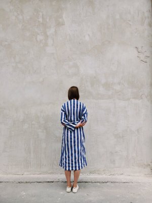 Foto de Radu Florin no Pexels Mulher parada em frente a um muro.