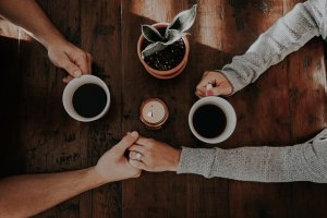 Foto de taylor hernandez no Unsplash Casal de mãos dadas tomando café.