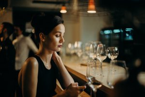 Foto de cottonbro no Pexels Mulher sozinha em um bar usando o celular.