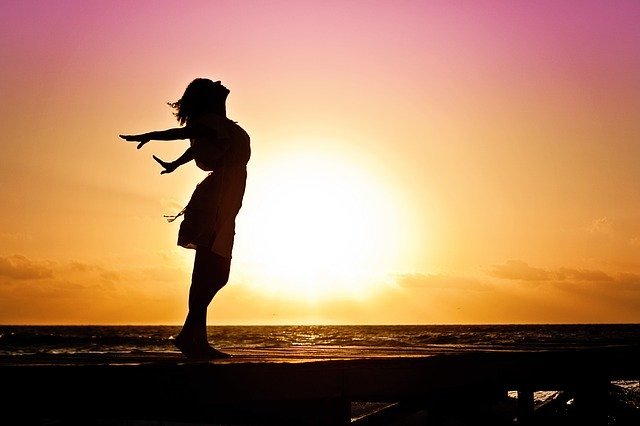 Pixabay/JillWellington Mulher de braços para trás e corpo projetado para frente com Sol ao fundo