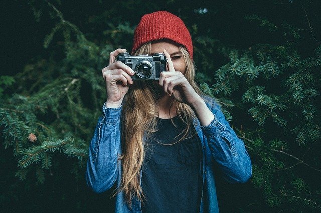 Menina com câmera fotográfica em frente ao rosto