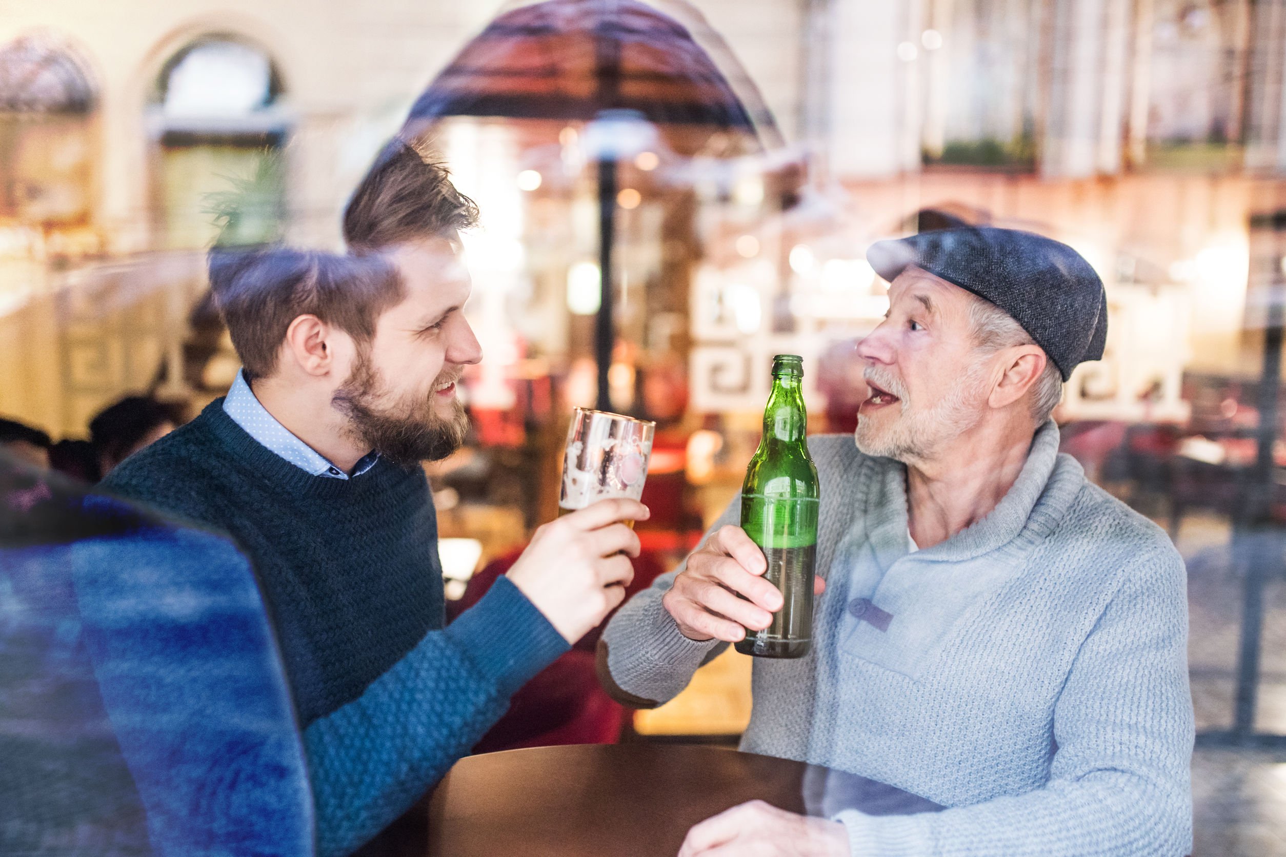 Dois homens bebendo cerveja em bar.