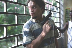 Divulgação Personagem Baiano de Tropa de Elite em pé segurando arma em bar