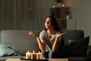123rf Mulher rezando diante de três velas na sala.