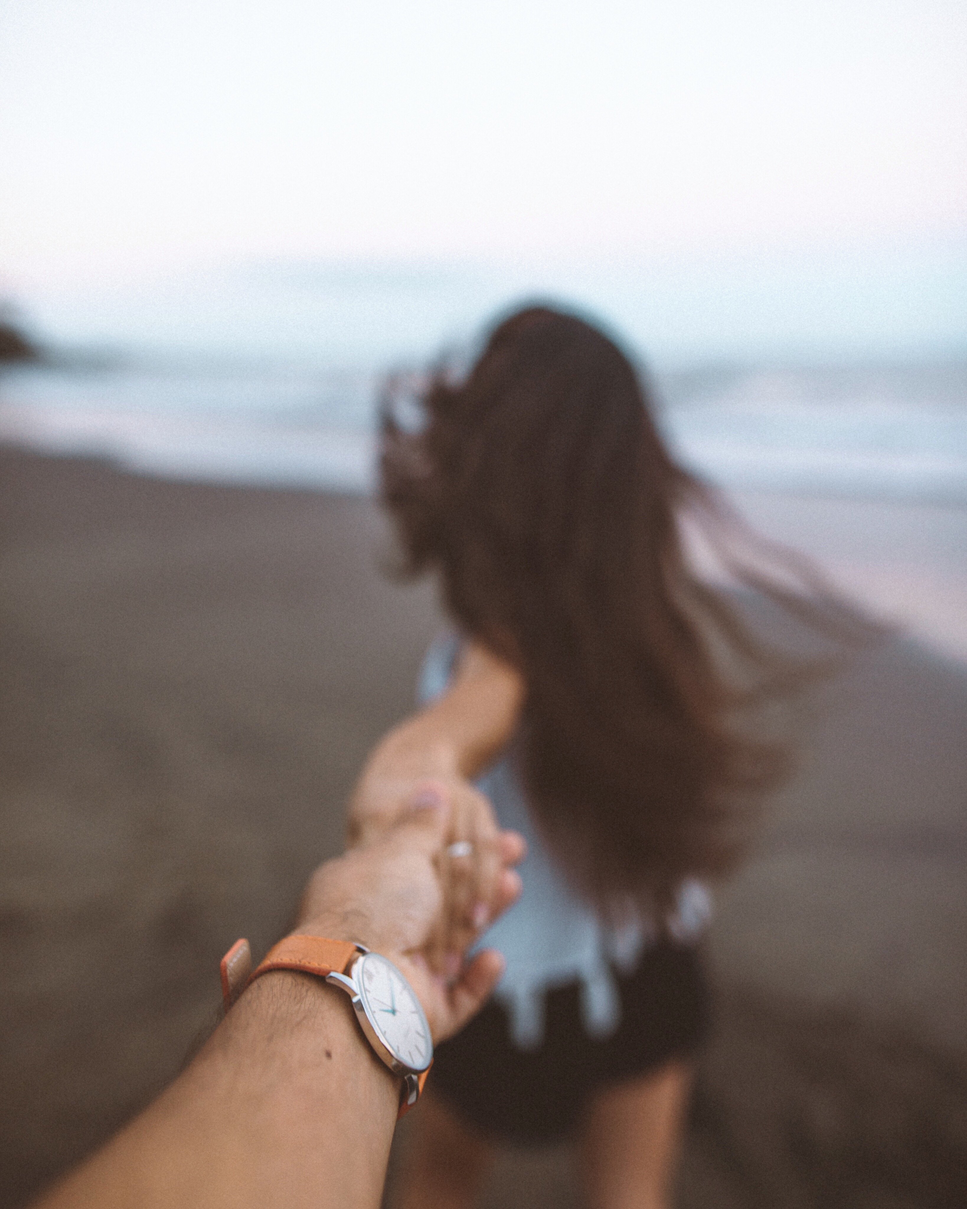 Pessoa segurando a mão de uma mulher na praia