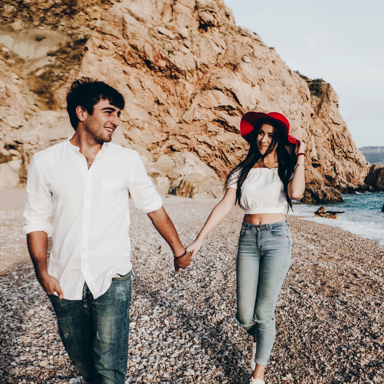 Homem e mulher com as mãos dadas andando na praia
