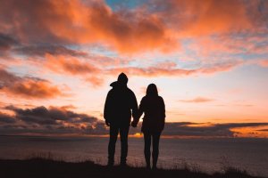 Unsplash/Alex Iby Casal de mãos dadas em crepúsculo