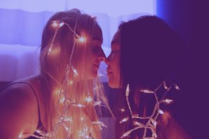 Unsplash/ Sharon McCutcheon Meninas com rostos próximos e enroladas em pisca-pisca