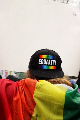 Pessoa com boné escrito Equality (igualdade, em inglês) com bandeira do arco íris
