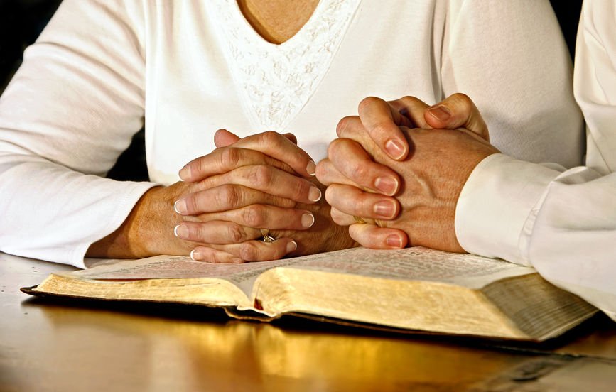 Casal com mão sobre a Bíblia