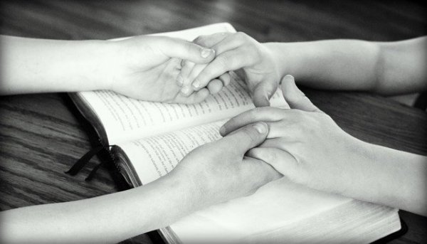 PixabayGodsgirl_madi Casal de mãos dadas sobre a Bíblia
