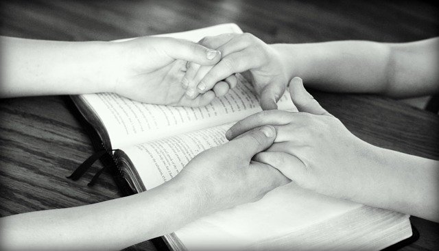 Casal de mãos dadas sobre a Bíblia