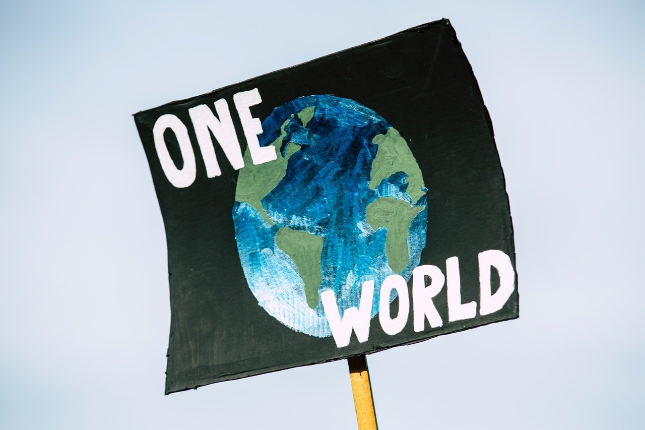 Placa de protesto com os escritos 'um só mundo' em inglês.