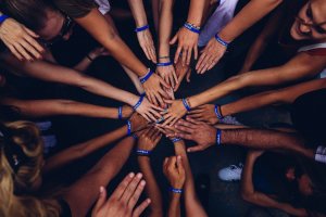 Foto de Perry Grone no Unsplash Grupo de voluntários unindo as mãos em um círculo.