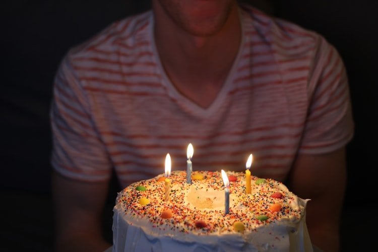 Homem atrás de bolo de aniversário