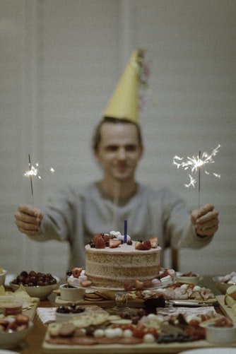 Homem com chapéu de festa e bolo de aniversário