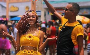Gabrielle Machado/Instagram Casal fantasiado de girassol, o homem joga confetes sobre a mulher.