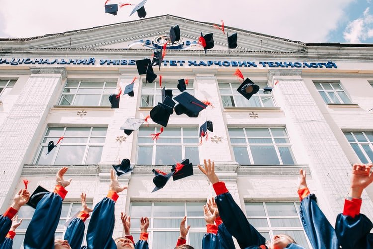Unsplash/Vasily Koloda Alunos graduados jogando chapéus de formatura