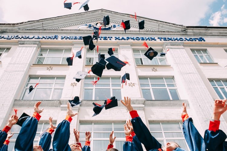 Alunos graduados jogando chapéus de formatura